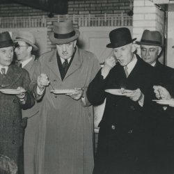 Groep mannen die haring eten.