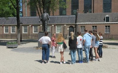 Museumdocent met groepje leerlingen op het Daniël Meijerplein