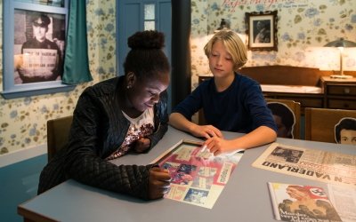 Twee kinderen in Verzetsmuseum Junior bekijken een scherm over propaganda
