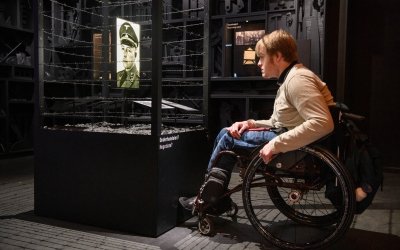 Een bezoeker in een rolstoel bekijkt een vitrine