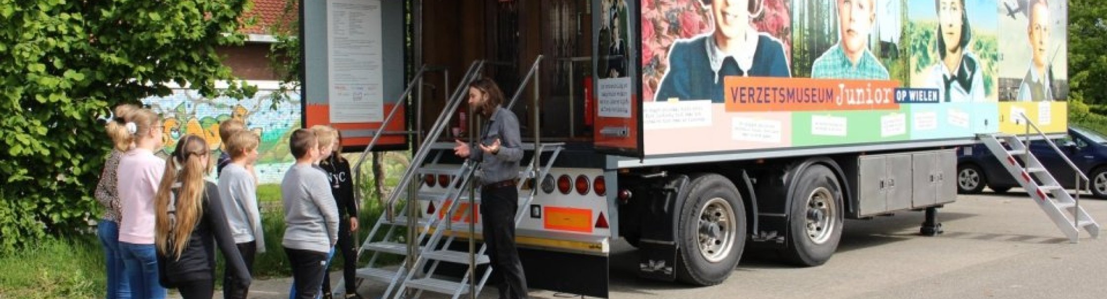 Kinderen staan voor de vrachtwagentrailer van het Verzetsmuseum Junior op Wielen