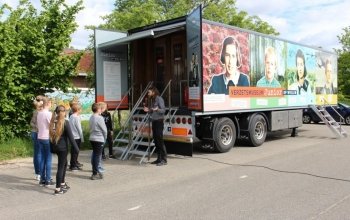 Kinderen worden voor de trailer ontvangen door een museumdocent.