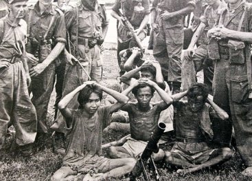 Nederlandse soldaten richten nonchalant hun wapens op soldaten van het Indonesische regeringsleger die zich hebben overgegeven. Solo, Midden-Java, 21 december 1948.