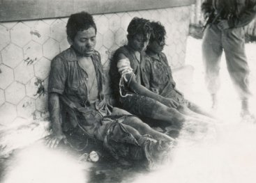 Drie Indonesische gevangenen worden bewaakt door een Nederlandse militair. Java, 27 november 1947.