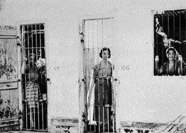 Women sitting on the floor, laundry is hanging from a clothes line.