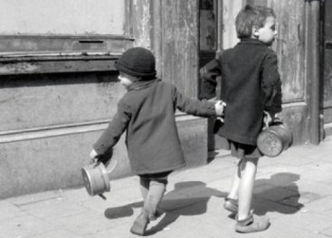 Twee kinderen die elkaars hand vasthouden en op weg zijn naar de boeren.